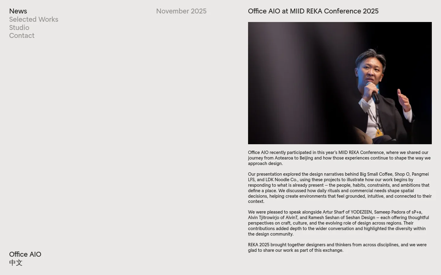 The News page features a minimalist design with a light grey background and dark text. The layout consists of a navigation menu on the left and a news feed on the right, starting with a large headline 'Office AIO at MIID REKA Conference 2025' accompanied by a photo of a man speaking into a microphone. Below the headline, several paragraphs of text describe the event.
