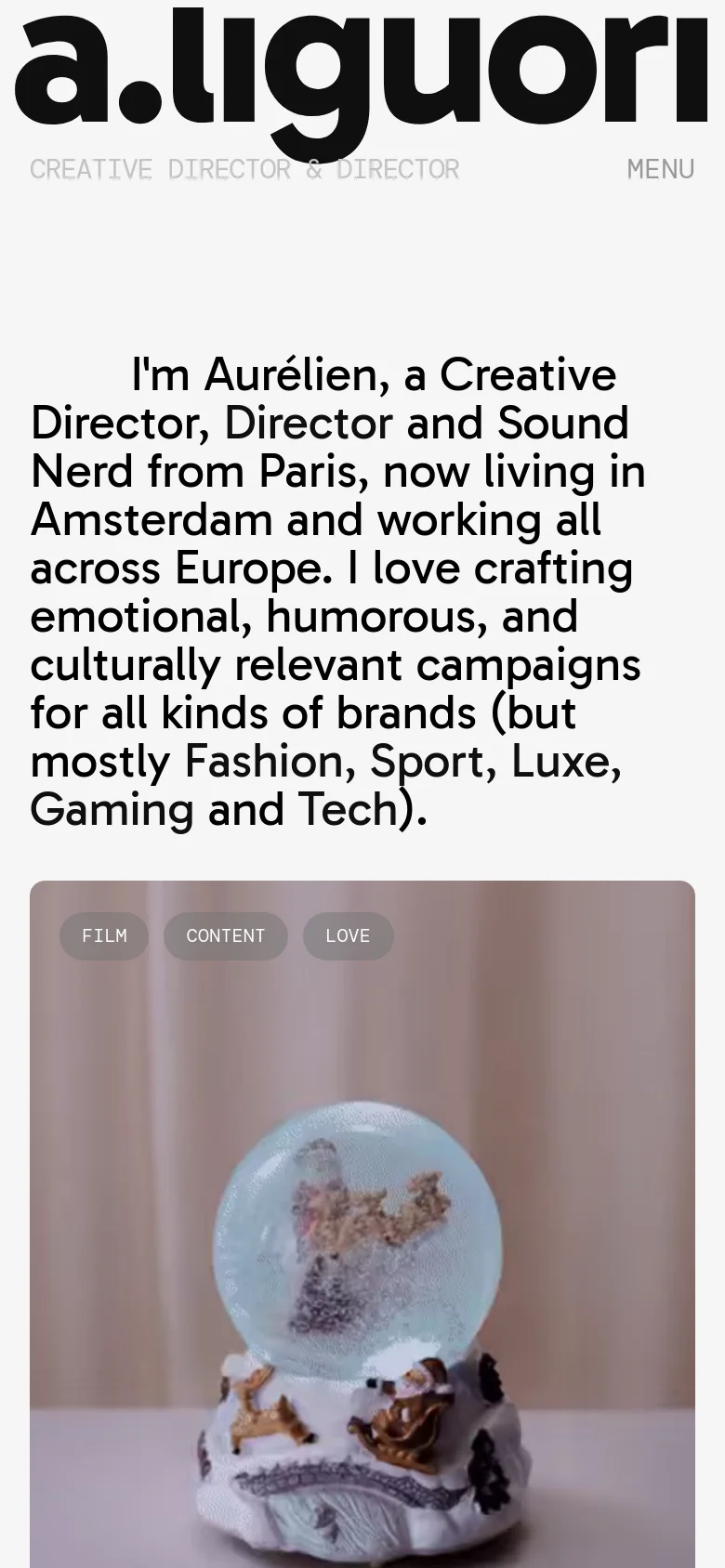 The mobile version maintains the minimalist aesthetic but uses a vertical single-column layout. The large header text and introductory bio are stacked vertically above a single-column feed of large project images. The top navigation is condensed into a 'MENU' link to save space on the smaller screen.