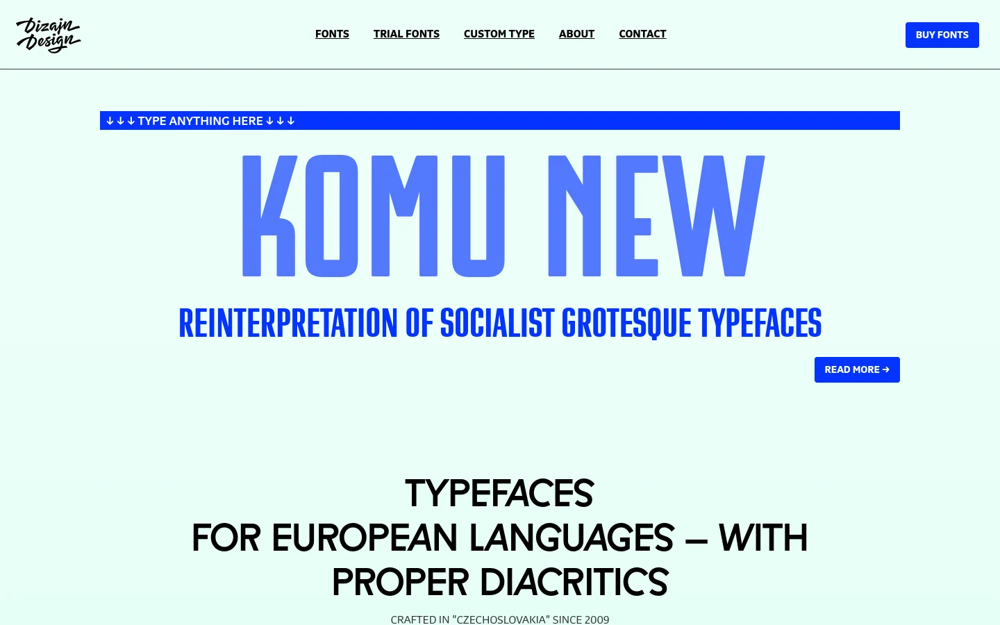 The desktop homepage for DizajnDesign features a clean, minimalist layout with a light mint green background. A large blue hero section displays the typeface 'KOMU NEW' in bold blue lettering, followed by a headline about European language typefaces. Navigation links for Fonts, Trial Fonts, and Custom Type are at the top, alongside a prominent 'BUY FONTS' button.