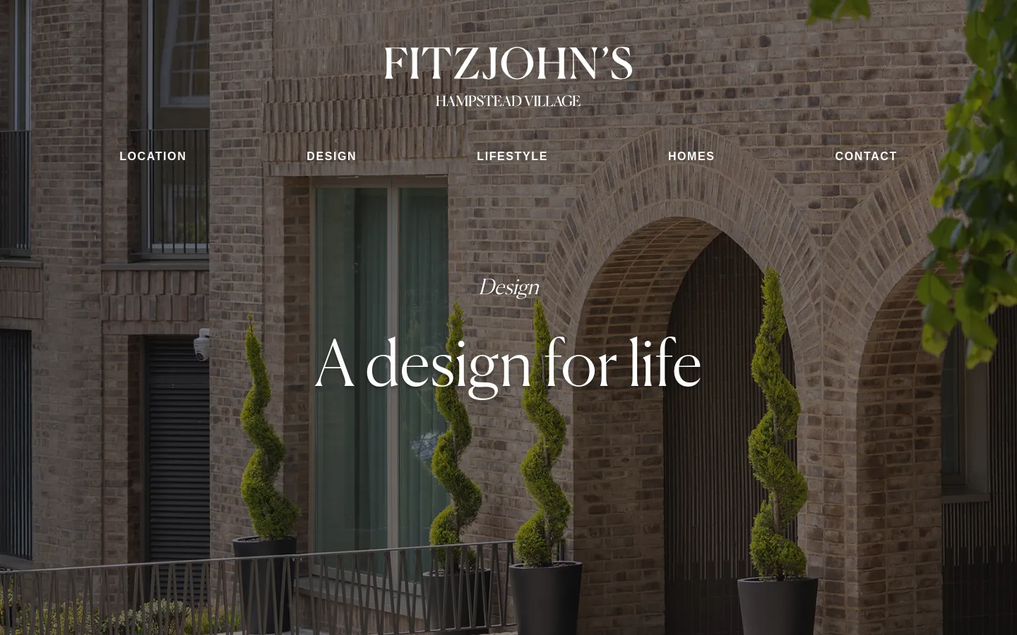 The desktop landing page features a full-width hero image of a modern brick building with arched entryways and spiral topiary trees. Centered white text displays the Fitzjohn's logo and the headline 'A design for life,' with a horizontal navigation menu below containing links for Location, Design, Lifestyle, Homes, and Contact.