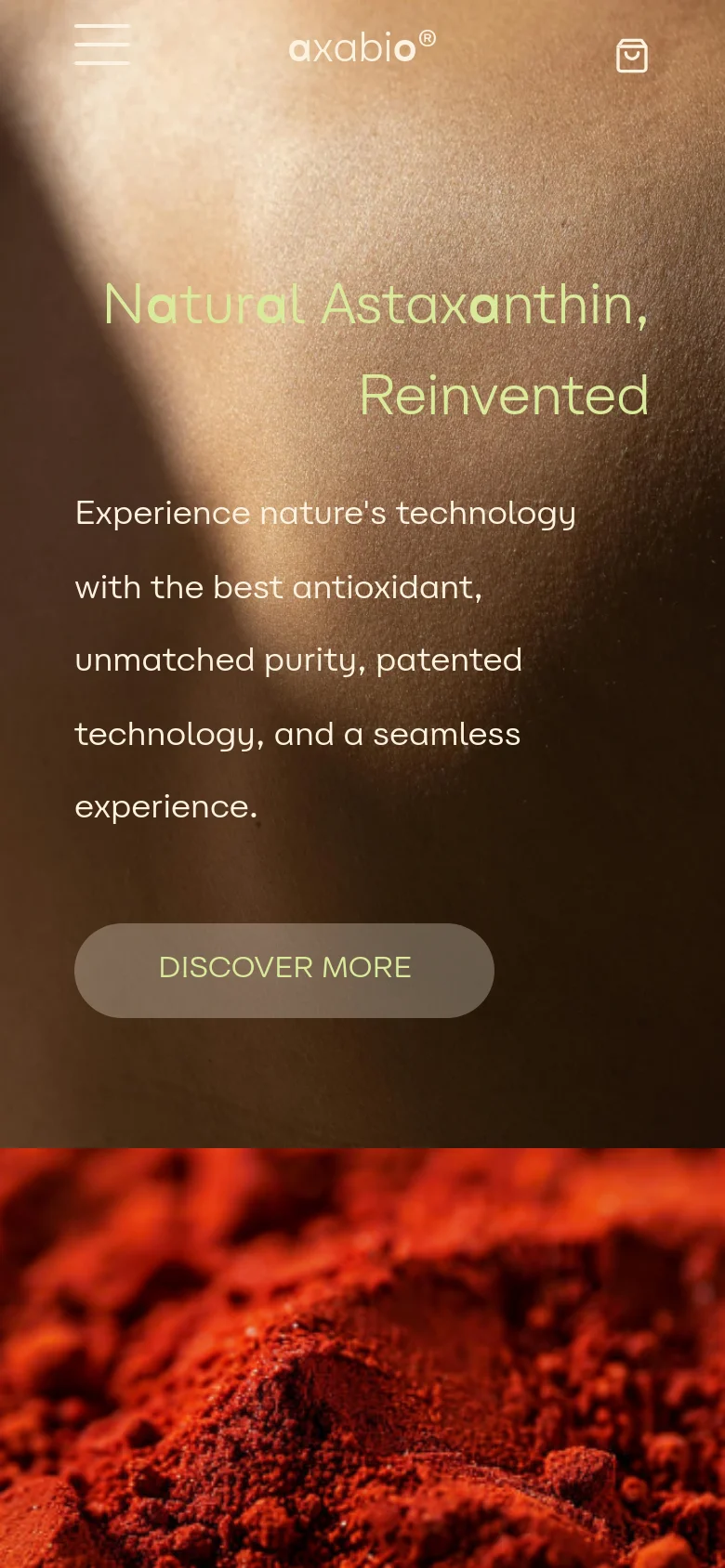 The mobile version presents a vertically stacked layout with a simplified navigation menu represented by a hamburger icon and a shopping bag icon. The hero section features the same headline and 'Discover More' button over a close-up portrait, but the text is centered and scaled for a smaller screen. The background imagery remains consistent with the desktop version, focusing on warm, natural tones and red antioxidant powder.