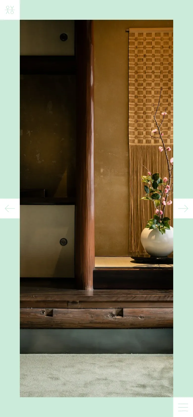 The mobile version maintains the mint green background but uses a vertical layout where the hero image of the Japanese interior occupies most of the screen. The navigation is condensed, replacing the top menu with a hamburger icon in the bottom right corner, and the footer links are stacked or simplified.