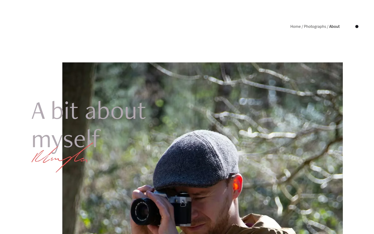 The desktop About page features a minimalist white layout with a large hero image of a man in a flat cap holding a camera against a blurred forest background. The headline 'A bit about myself' is overlaid on the image in large grey text with a red signature underneath. Navigation links for Home and Photographs are located in the top right corner.