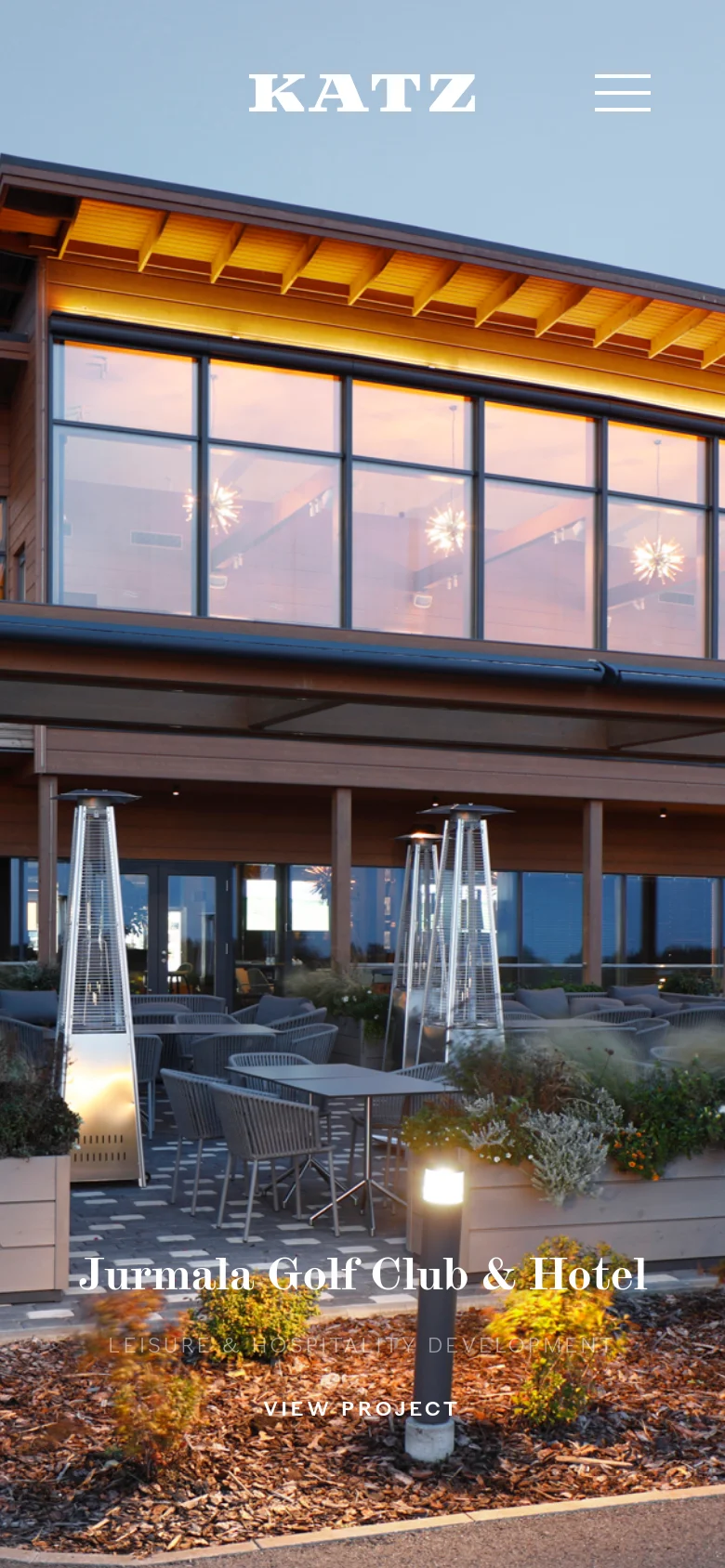 The mobile version shows a vertically oriented, zoomed-in view of the hero building and patio area. The Katz logo is centered at the top, accompanied by a hamburger menu icon on the right, and the project title and 'View Project' call to action are positioned at the bottom over the image.