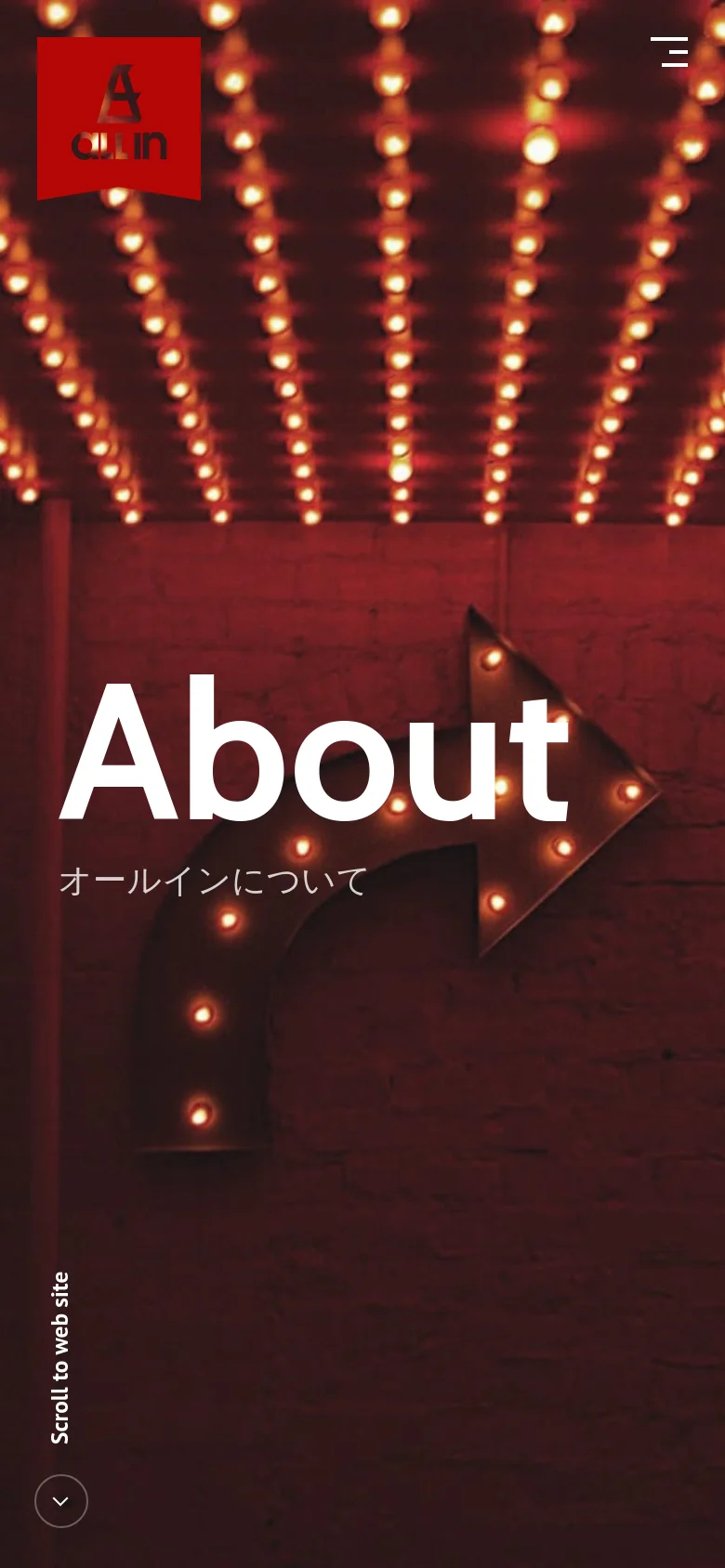 The mobile version simplifies the layout, replacing the top navigation bar with a hamburger menu icon in the upper right. The red hero section remains dominant, featuring the large 'About' headline and marquee lights, but the red company logo is larger and positioned on the left. The 'Scroll to web site' text and arrow are positioned vertically at the bottom left.