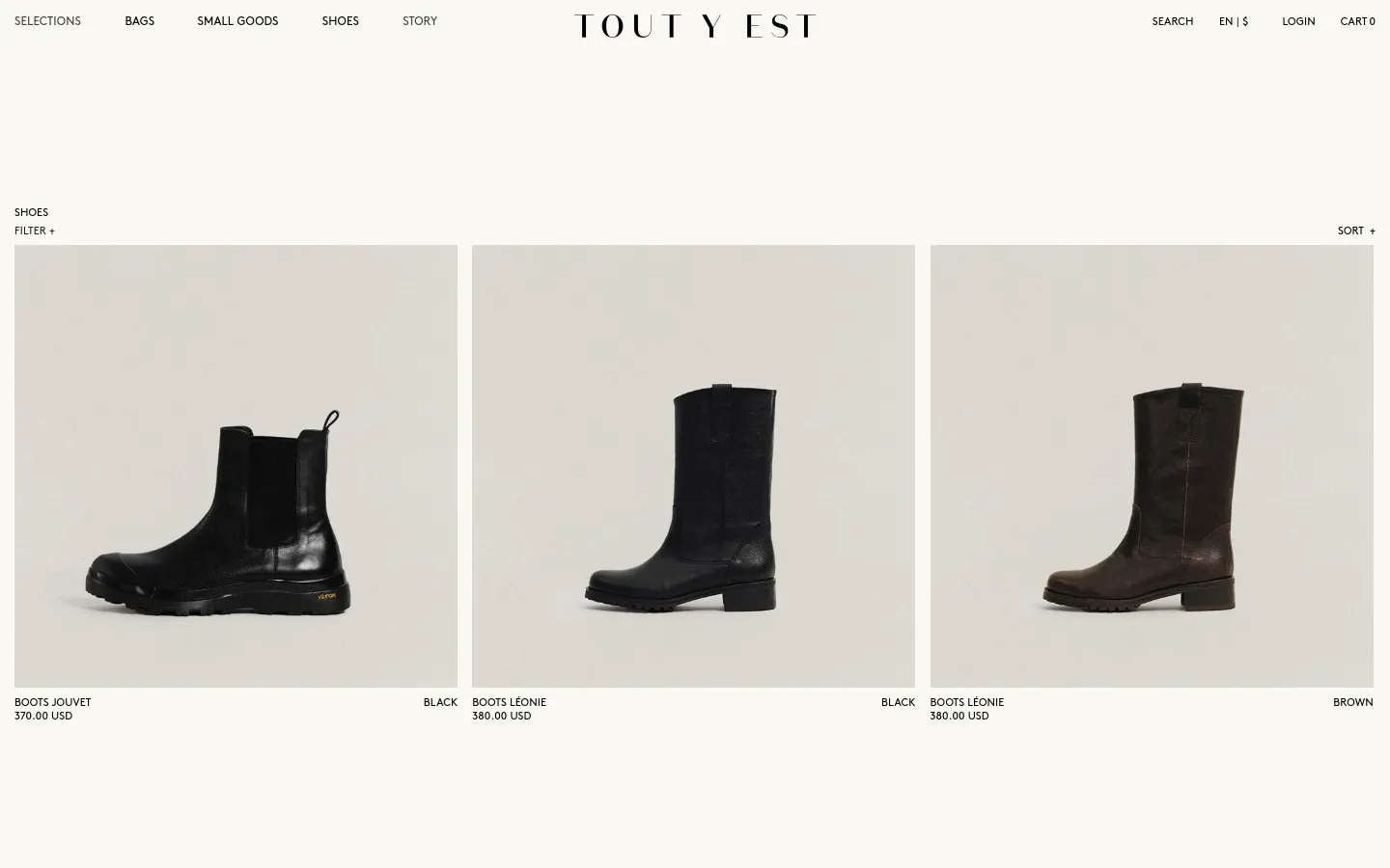 The desktop version of the Shoes collection page features a minimalist design with a white background and black serif typography. A navigation bar at the top includes links for Bags, Small Goods, Shoes, and Story, alongside a central brand logo. The main content displays a grid of product images showing various black and brown leather boots, with product names and prices listed below each item.
