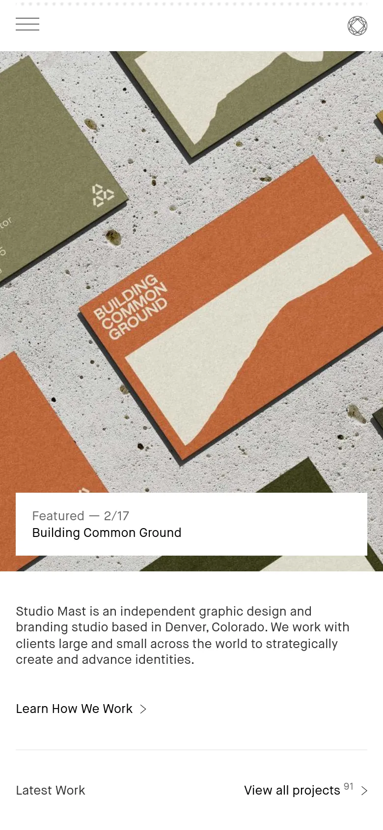 The mobile version simplifies the layout with a hamburger menu icon and a circular logo in the header. The hero section maintains the textured stationery imagery but uses a centered white overlay box to display the featured project title and progress indicator.