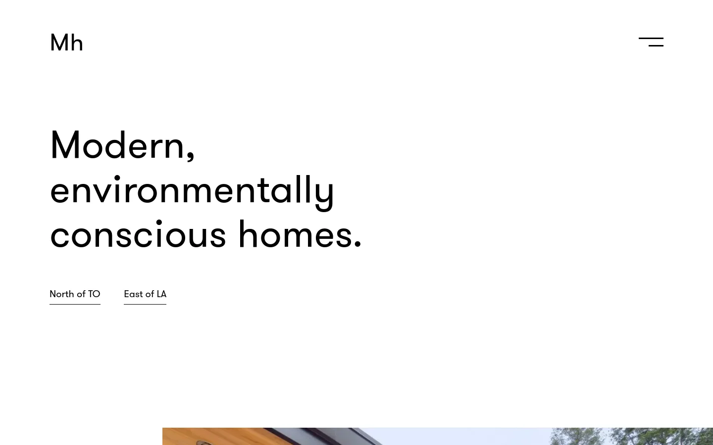 The desktop homepage features a minimalist white background with the 'Mh' logo and a hamburger menu icon at the top. A large, bold headline reads 'Modern, environmentally conscious homes,' positioned above two text-based call-to-action links: 'North of TO' and 'East of LA.'
