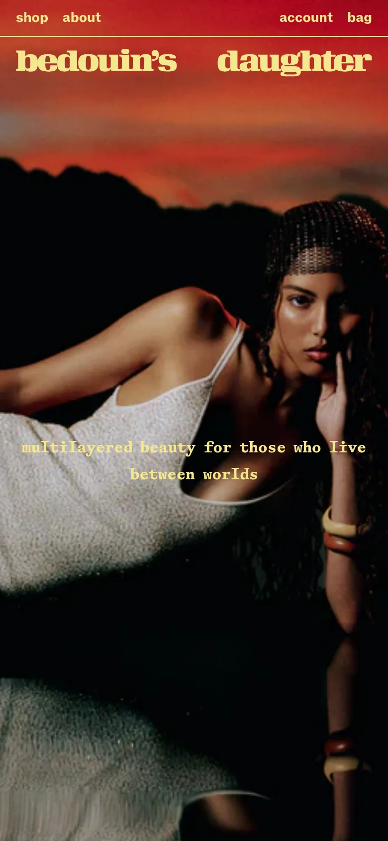 The mobile version presents a vertically oriented view of the hero image, focusing on the woman in the shimmering dress against the sunset background. The brand name remains prominent at the top in cream serif text, while the navigation links are condensed to fit the narrower screen width. The overall aesthetic maintains the dark, high-contrast, and luxurious feel of the desktop site.