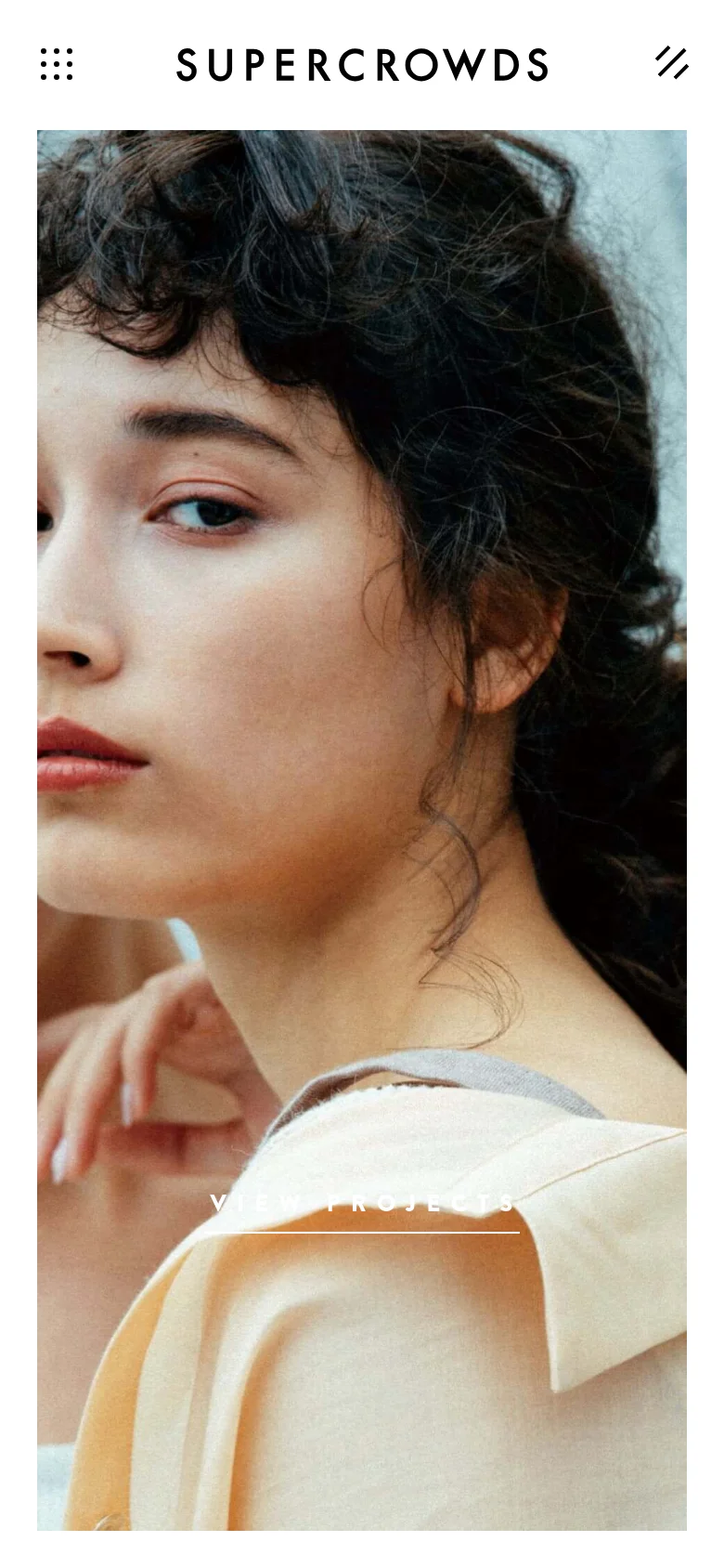 The mobile version presents a full-screen close-up portrait of a person as the hero image against a light background. The 'SUPER CROWDS' logo is centered at the top, with a menu icon and a 'VIEW PROJECTS' call to action positioned above and within the image area.
