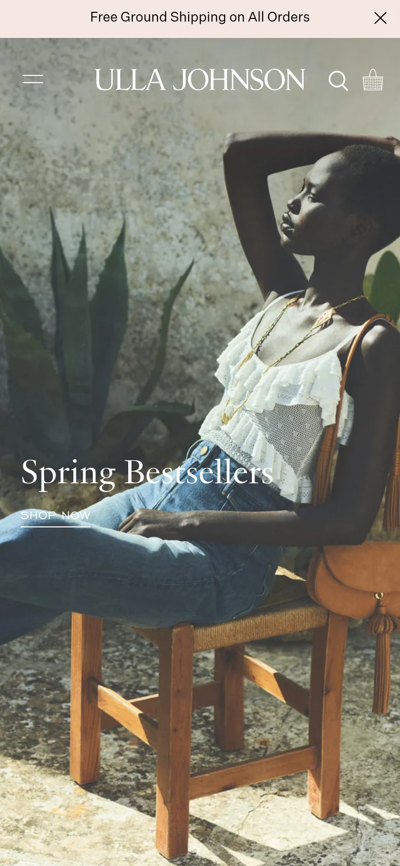 The mobile version presents a vertically oriented hero image of the same woman, with the 'Spring Bestsellers' headline and 'SHOP NOW' link positioned centrally over the subject. The layout is simplified with a hamburger menu icon on the top left, the brand logo centered, and search and shopping bag icons on the top right.