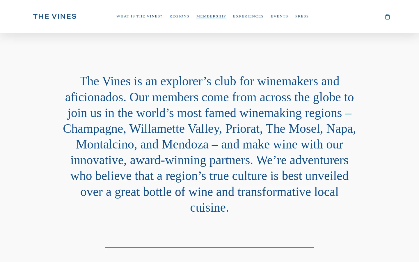The About Us page features a minimalist design with a white background and dark blue serif typography. A large, centered hero text block describes The Vines as an explorer’s club for winemakers, followed by a section titled 'A FEW OF OUR MEMBERS' which includes a portrait of Carlos Garcia and his biography. The desktop navigation bar at the top includes links for 'What is The Vines?', 'Regions', 'Membership', 'Experiences', 'Events', and 'Press', alongside a shopping bag icon.