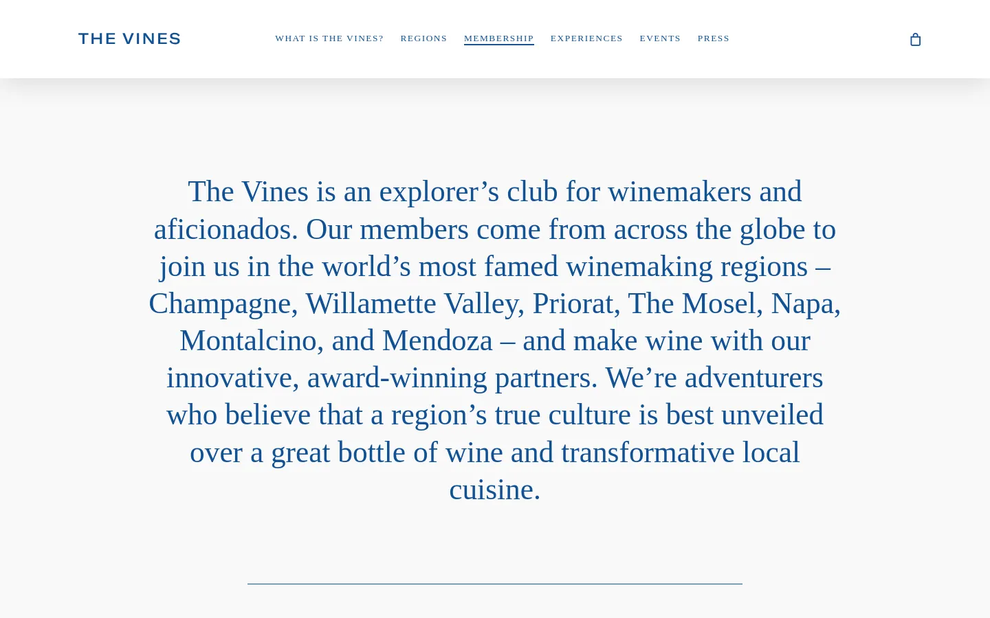 The About Us page features a minimalist design with a white background and dark blue serif typography. A large, centered hero text block describes The Vines as an explorer’s club for winemakers, followed by a section titled 'A FEW OF OUR MEMBERS' which includes a portrait of Carlos Garcia and his biography. The desktop navigation bar at the top includes links for 'What is The Vines?', 'Regions', 'Membership', 'Experiences', 'Events', and 'Press', alongside a shopping bag icon.