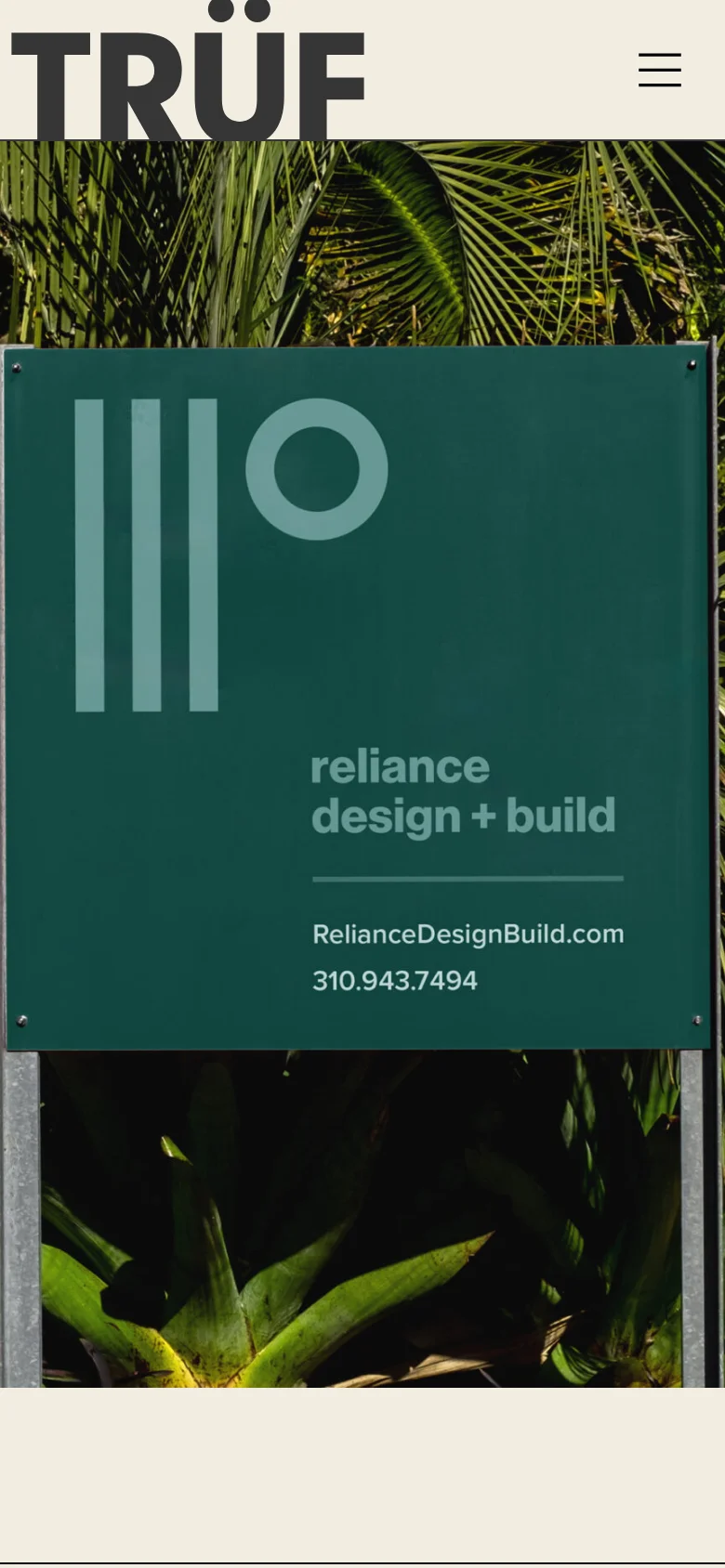 The mobile version features a simplified cream header with the large TRÜF logo and a three-line hamburger menu icon for navigation. The hero section shows a vertically oriented version of the dark green 'reliance design + build' sign, framed by lush tropical foliage. The layout shifts from a wide horizontal view to a stacked, portrait-oriented presentation optimized for vertical scrolling.