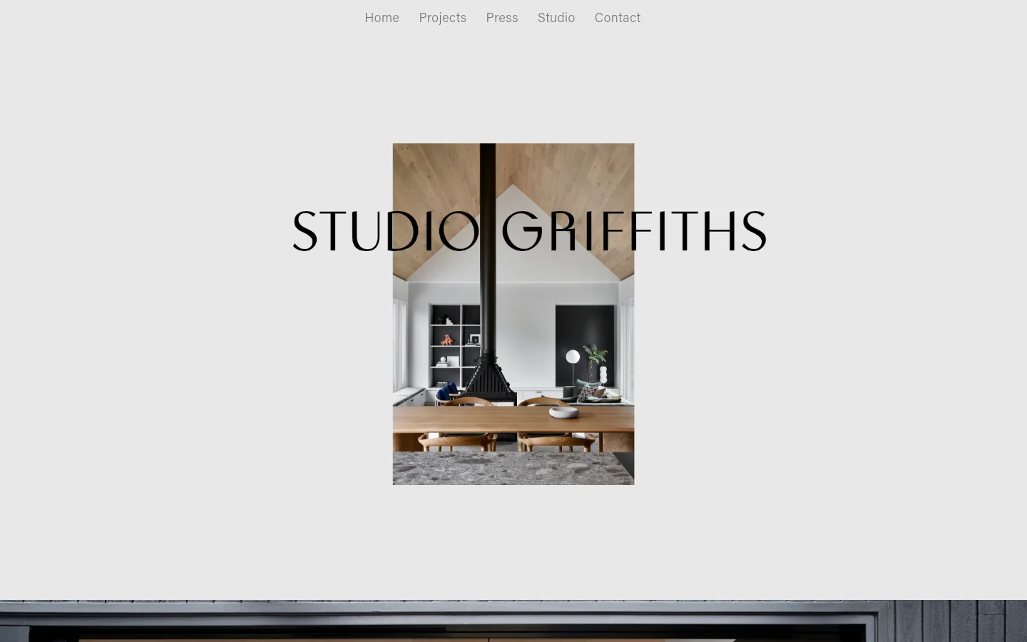 The desktop homepage features a minimalist design with a light grey background. The 'STUDIO GRIFFITHS' logo is centered over a vertical rectangular hero image of a modern interior with a wood ceiling and a black fireplace, with a navigation menu above it containing links for Home, Projects, Press, Studio, and Contact.
