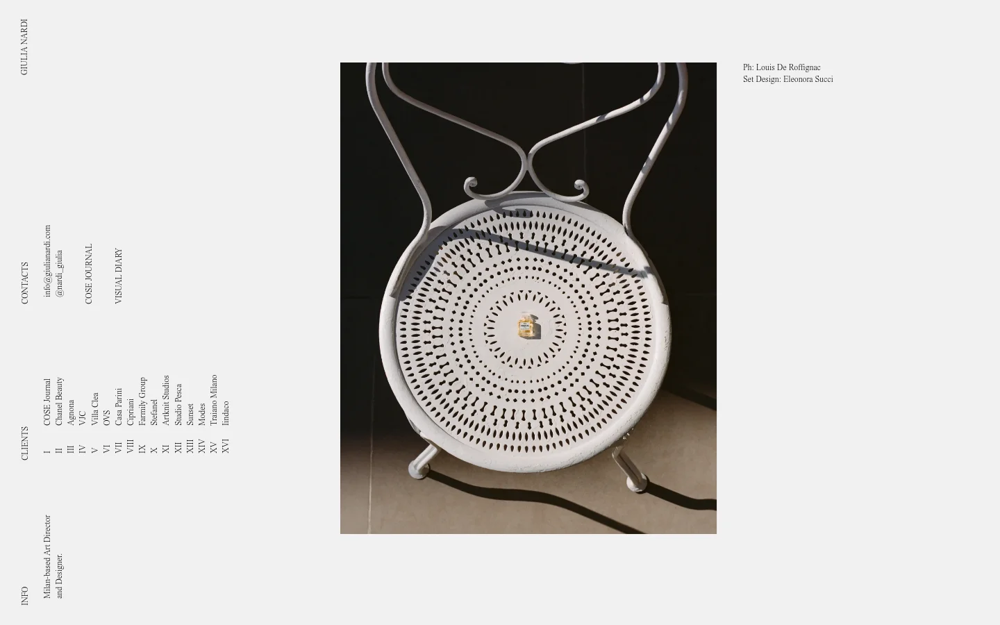 The desktop page features a minimalist design with a large, high-resolution editorial photograph of a white wrought-iron chair holding a small gold cosmetic product. The layout uses a clean white background with vertical navigation text on the left and the brand name 'GIULIA NARDI' at the top left. Credits for photography and set design are positioned in the upper right corner.