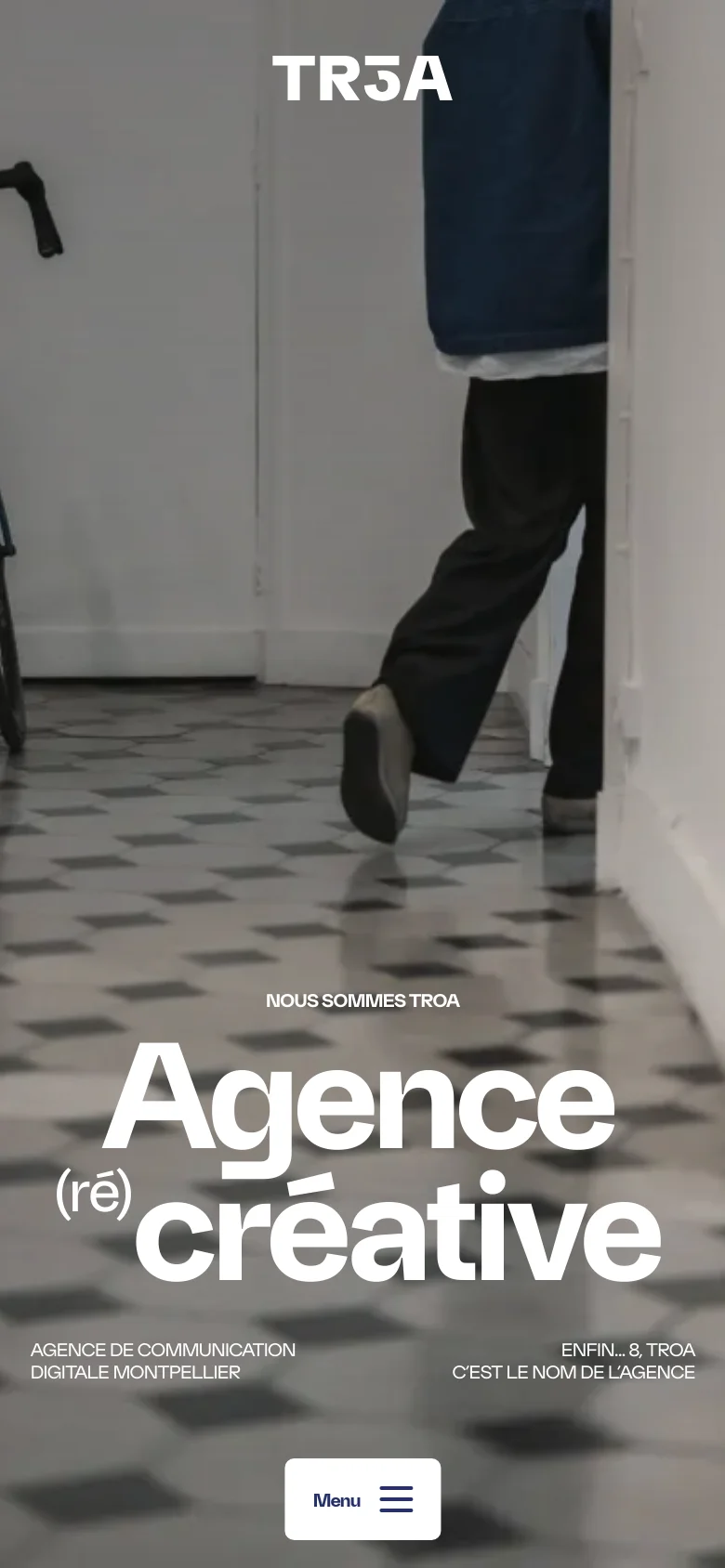 The mobile version simplifies the layout, replacing the top navigation bar with a centered 'Menu' button at the bottom. The hero section remains dominant, featuring the large white 'Agence (ré) créative' headline over a vertical, cropped version of the office photography. Text elements are stacked vertically to fit the narrow screen.