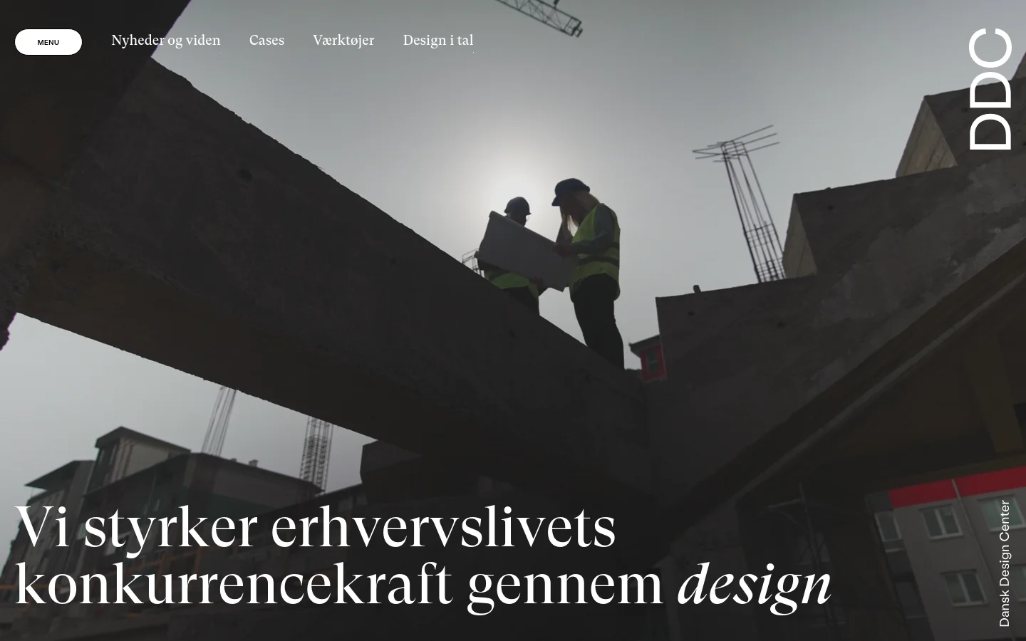 The desktop homepage features a large hero image of construction workers in silhouette against a bright sky, overlaid with the headline 'Vi styrker erhvervslivets konkurrencekraft gennem design'. A white navigation bar at the top includes links for news, cases, tools, and design statistics, alongside a 'menu' button and the DDC logo. The layout is clean with a minimalist aesthetic and high-contrast white text on a dark background.