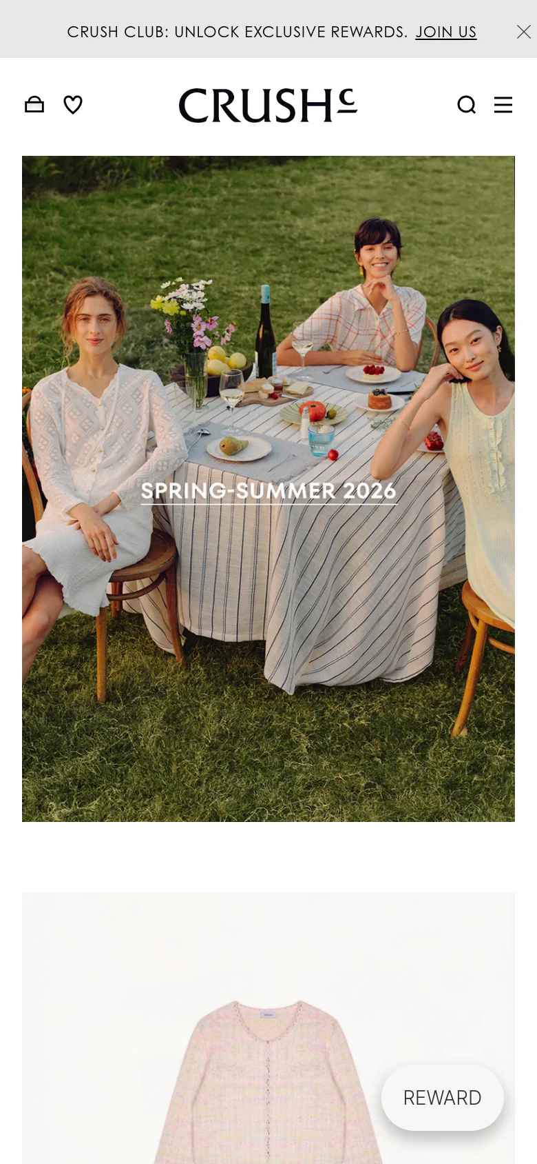 The mobile version presents a single-column layout optimized for vertical scrolling, starting with a large hero image of women at a garden table with 'SPRING-SUMMER 2026' text overlay. The top navigation is condensed into a hamburger menu icon on the right, with a shopping bag and heart icon on the left, and the brand logo centered. A prominent 'REWARD' floating button appears at the bottom right.