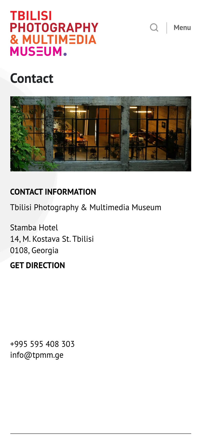 The mobile version simplifies the layout into a single vertical column on a white background. The red museum logo and a search icon appear at the top, followed by the 'Contact' heading, the window view hero image, and the contact information stacked vertically below.
