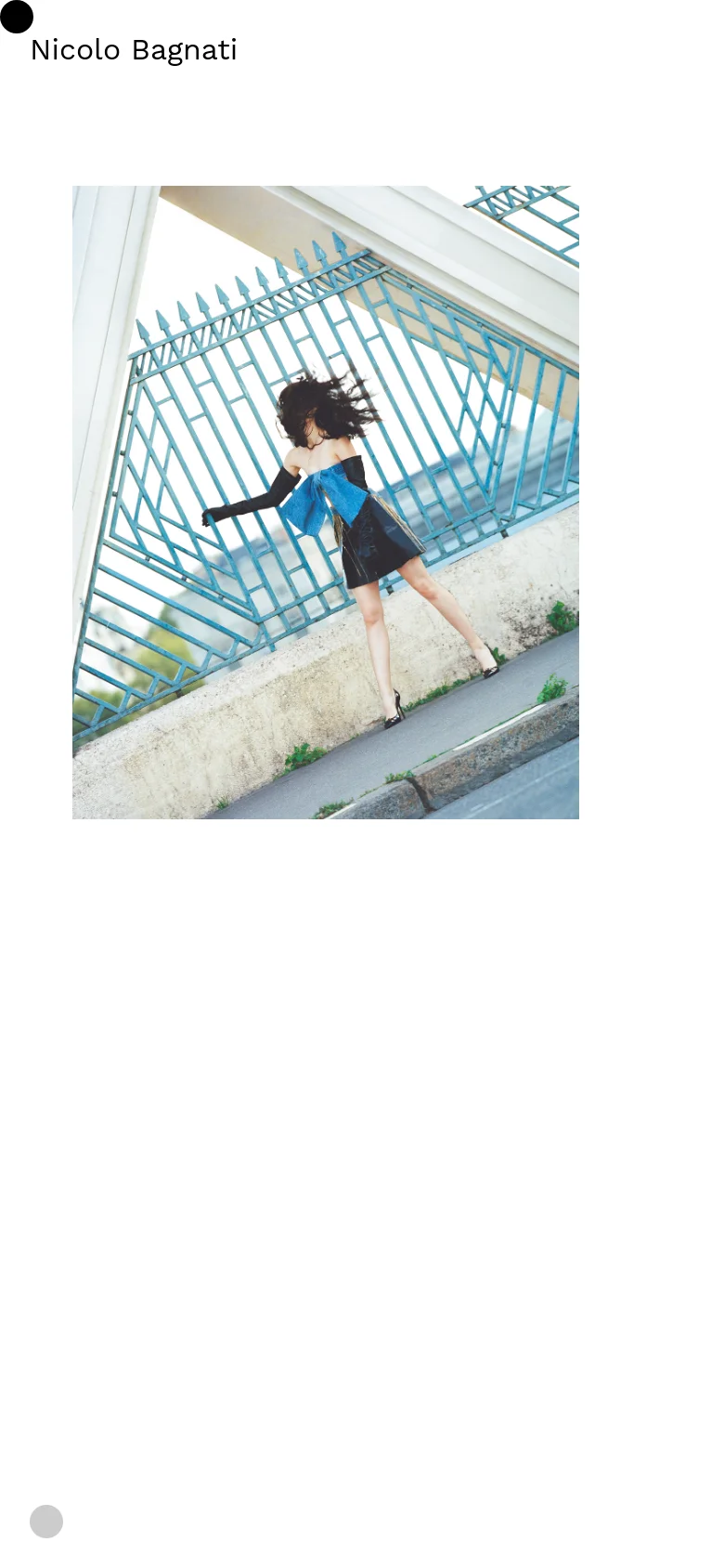 The mobile version maintains the minimalist white aesthetic and the name 'Nicolo Bagnati' at the top. The central high-fashion image is scaled to fit the vertical screen, showing a woman in a black dress leaning against a blue fence.