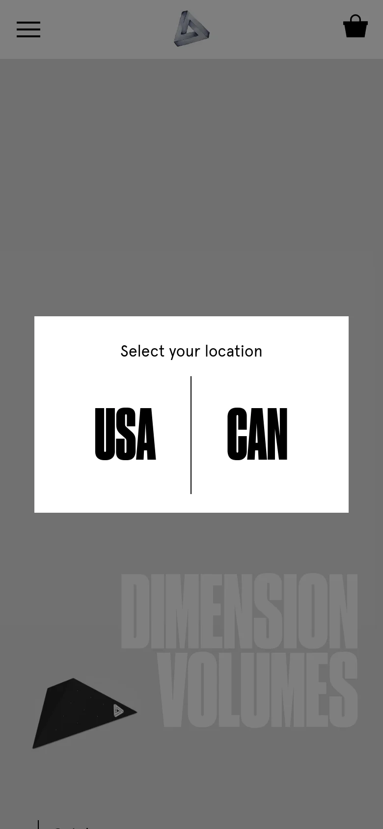 The mobile version maintains the minimalist gray aesthetic and the central 'Select your location' modal with 'USA' and 'CAN' options. The layout is vertically stacked, featuring a hamburger menu icon on the top left, the brand logo in the center, and a shopping bag icon on the top right. The large background text and 3D climbing volume are scaled to fit the narrower screen.