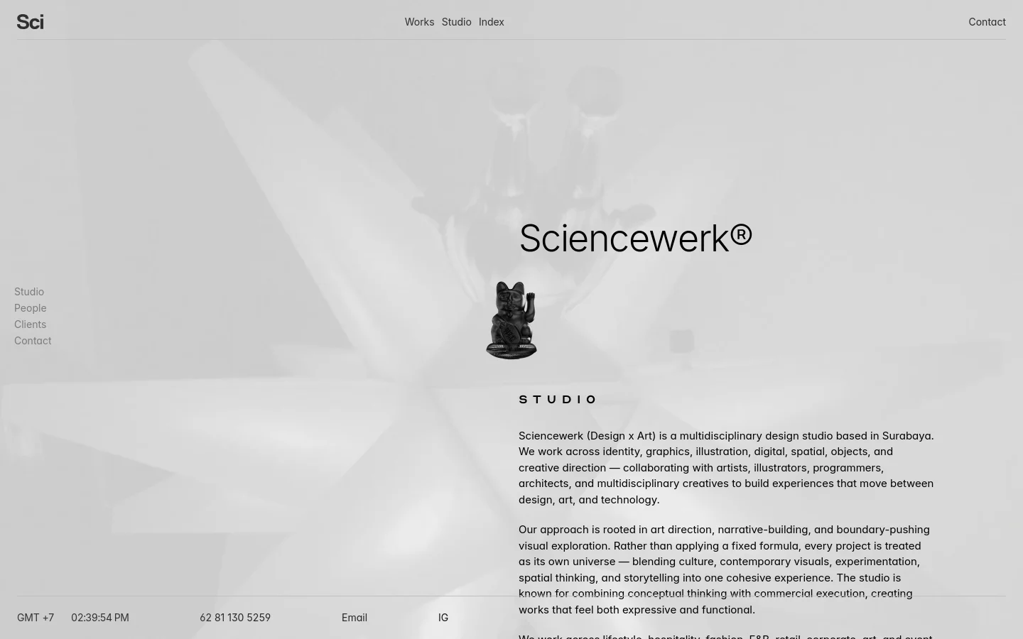 Desktop view of the Sciencewerk About page featuring a minimalist, grayscale design. A large hero section displays the title 'Sciencewerk®' over a faded background image of a studio space, centered around a small black cat figurine. Navigation links for Works, Studio, Index, and Contact are at the top, with a secondary vertical menu on the left and studio description text below.